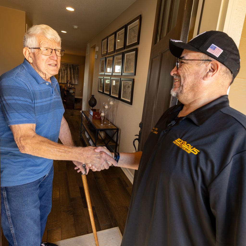 Two men shaking hands in a home entrance.