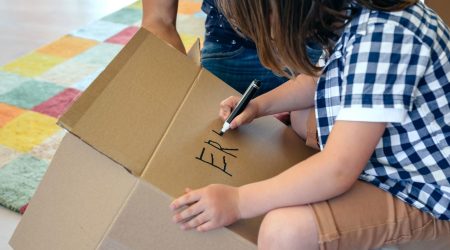 Little boy writing his name in a moving box with his father